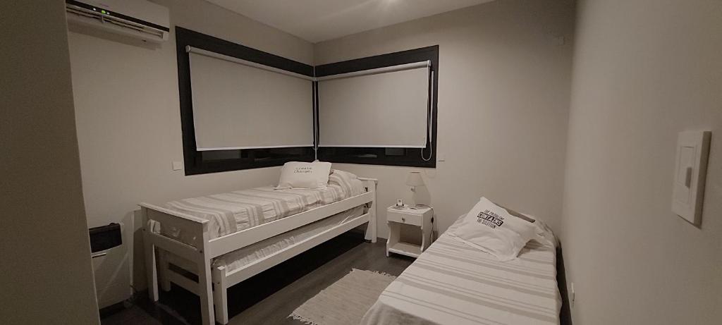 a small room with two beds and a window at Casa Cardales MINI PISCINA CLIMATIZADA in Sierra de la Ventana