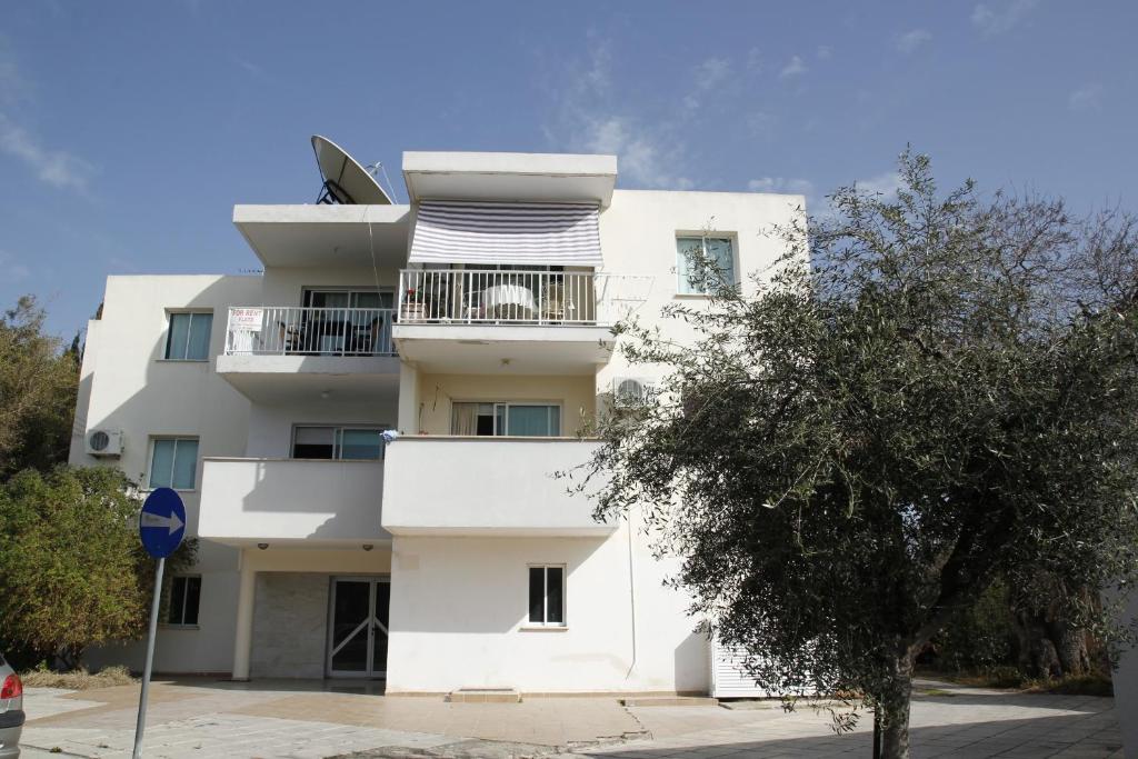 a white building with a tree in front of it at Faneromeni Court in Paphos City