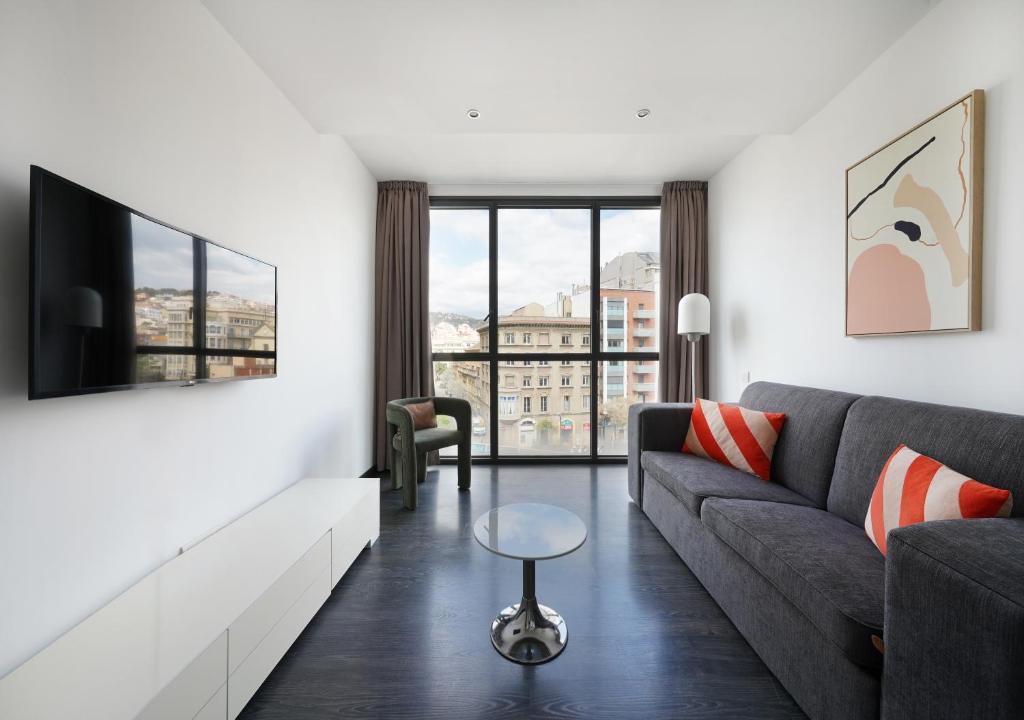 numa I Colmena Apartments في برشلونة: غرفة معيشة مع أريكة وتلفزيون