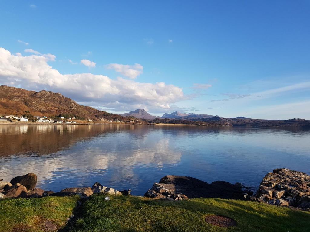 una gran masa de agua con montañas en el fondo en Port House, en Gairloch