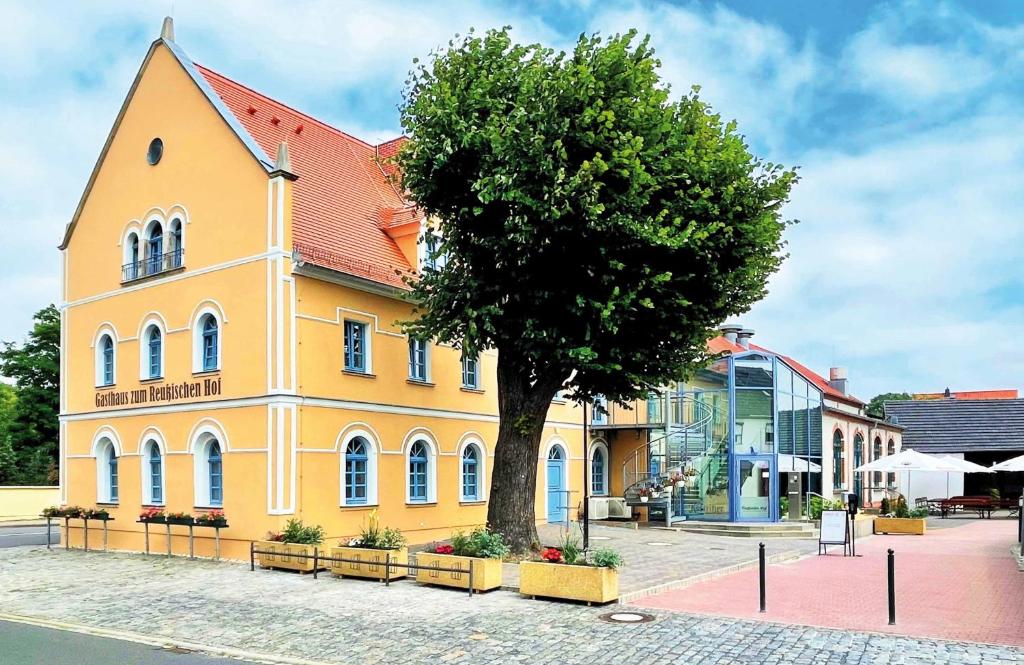 um edifício amarelo com uma árvore em frente em Pension "Zum Reußischen Hof" em Thallwitz