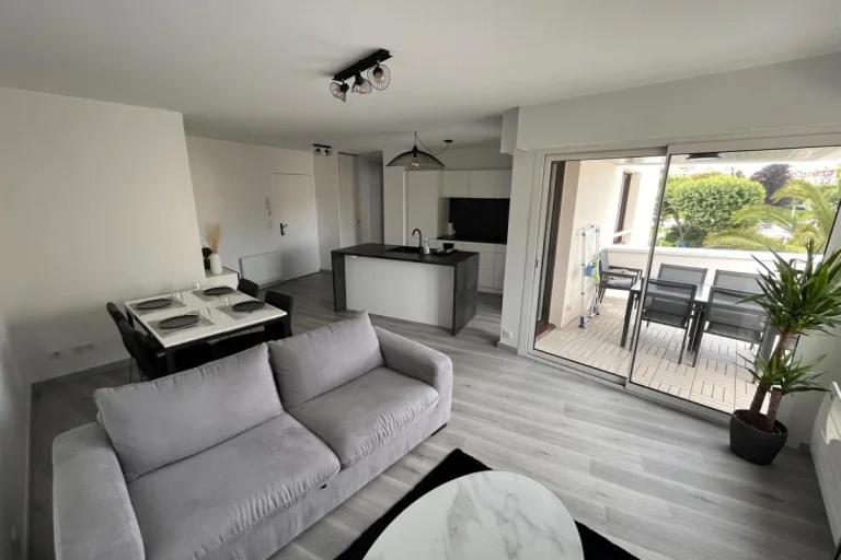 a living room with a white couch and a kitchen at Apartment hyper-center Biarritz with parking in Biarritz