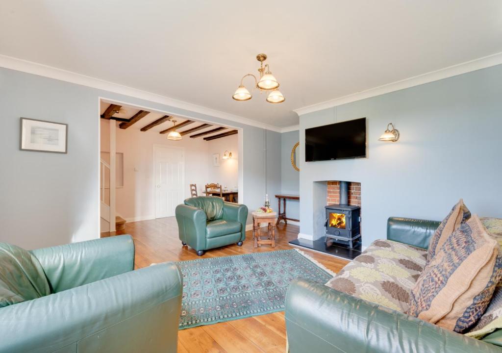uma sala de estar com mobiliário azul e uma lareira em 2 Mill Farm em Belchamp Otten