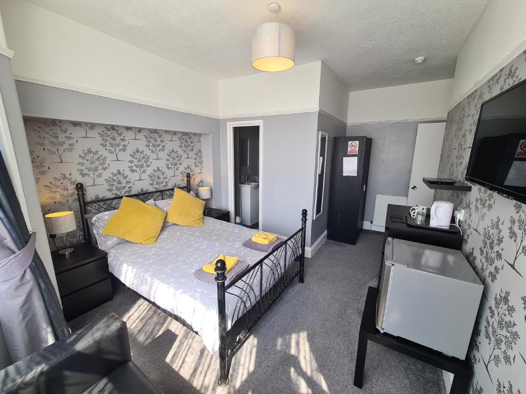 a bedroom with a bed with yellow pillows and a tv at The Roslyn Guest House in Paignton