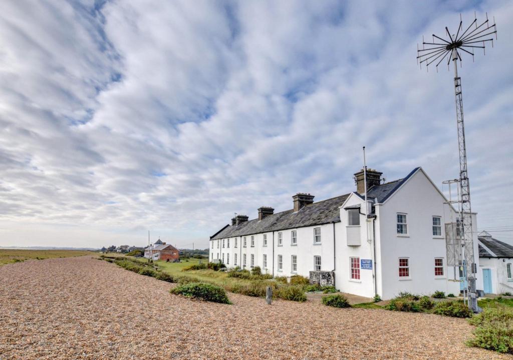 a white house on the beach with a windmill at 6 Coastguard Cottages in Hollesley