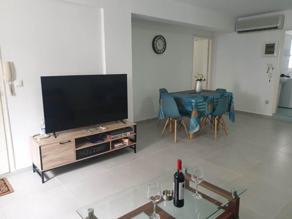 a living room with a flat screen tv and a table at Nikolas Family Apartments in Moírai