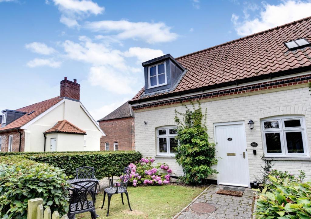 ein weißes Cottage mit einem Garten davor in der Unterkunft Amrose Cottage in Blythburgh