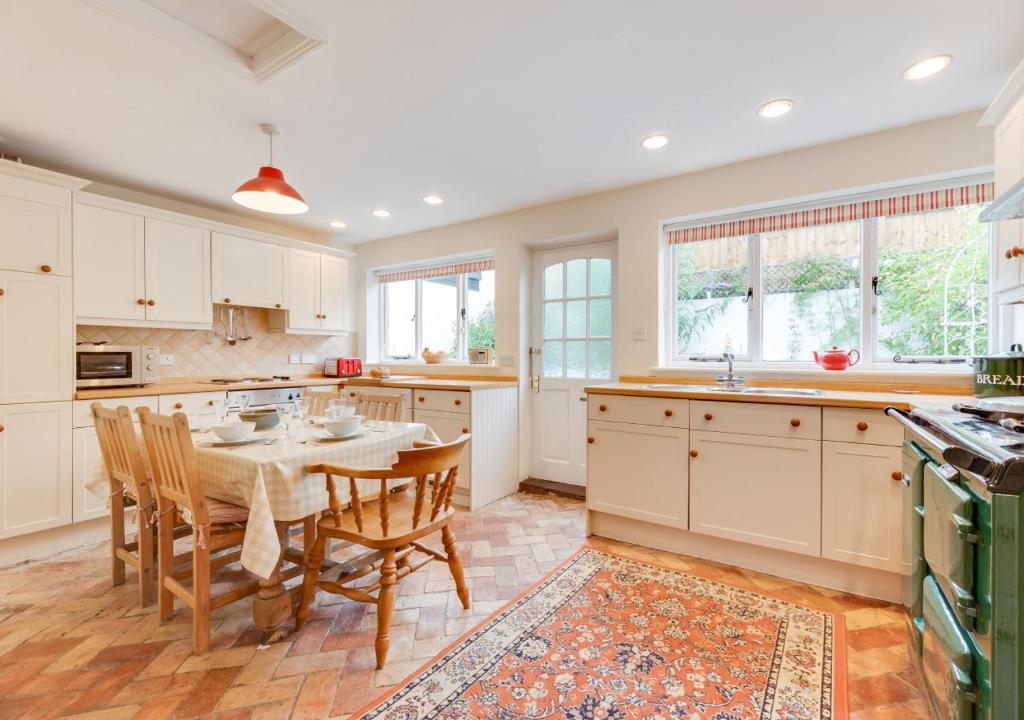 a kitchen with a table and chairs and windows at Anchor Cottage in Woodbridge