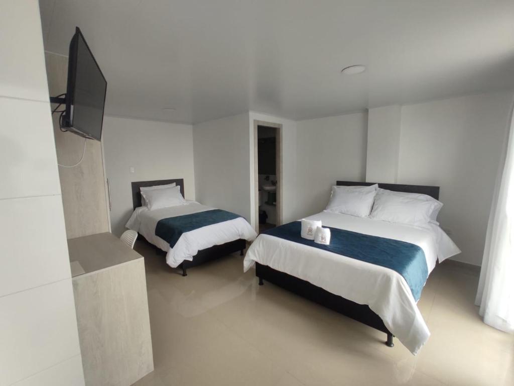 1 dormitorio con 2 camas y TV de pantalla plana en Hotel Meraki Popayán en Popayán