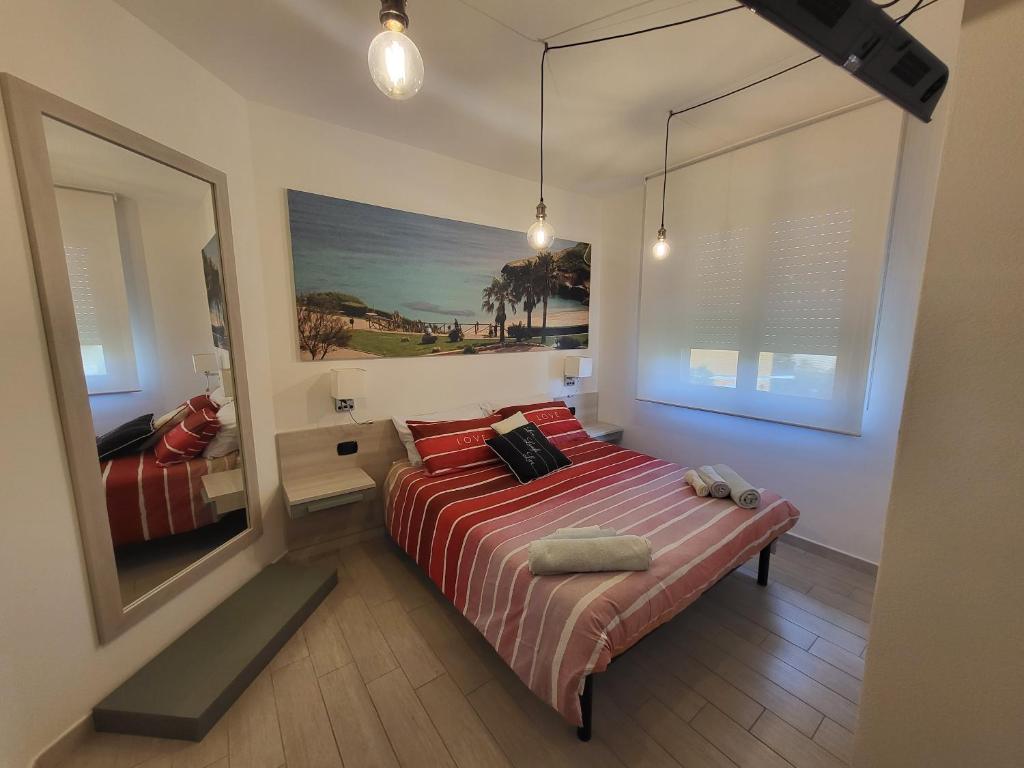 una camera da letto con un letto con lenzuola rosse e uno specchio di Struttura Re Barbaro a Porto Torres