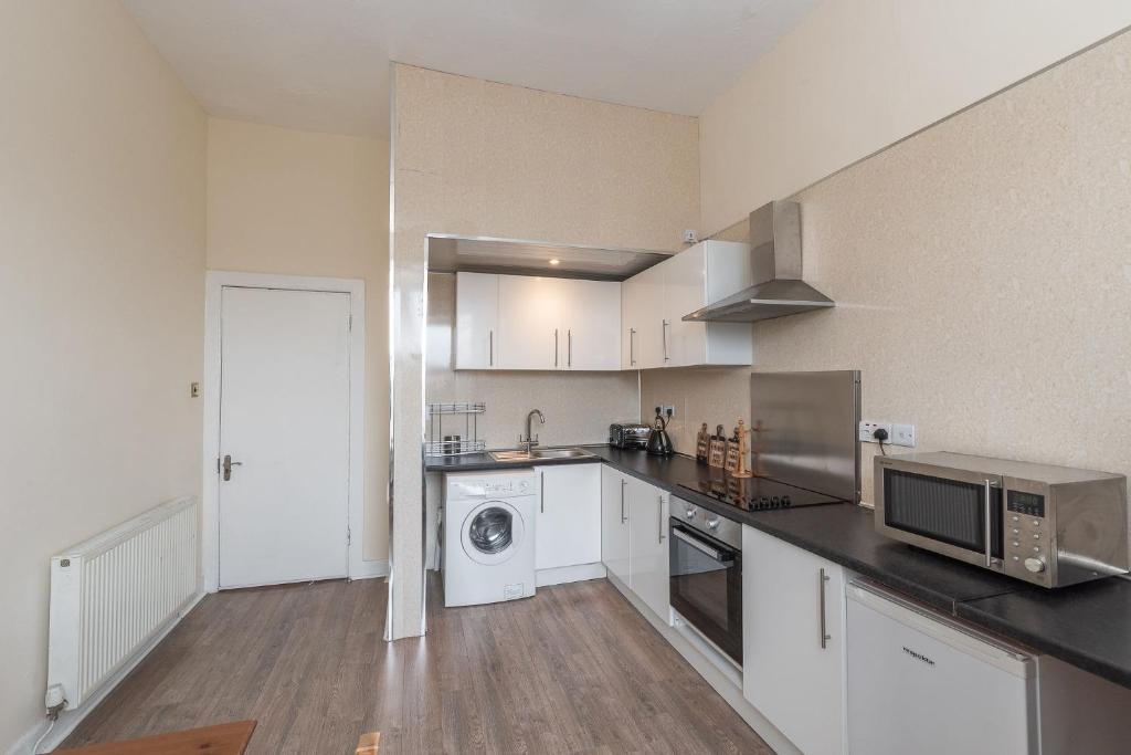 a kitchen with white cabinets and a microwave at Spacious Ensuite Rooms in Edinburgh City Centre - Excellent Location in Edinburgh