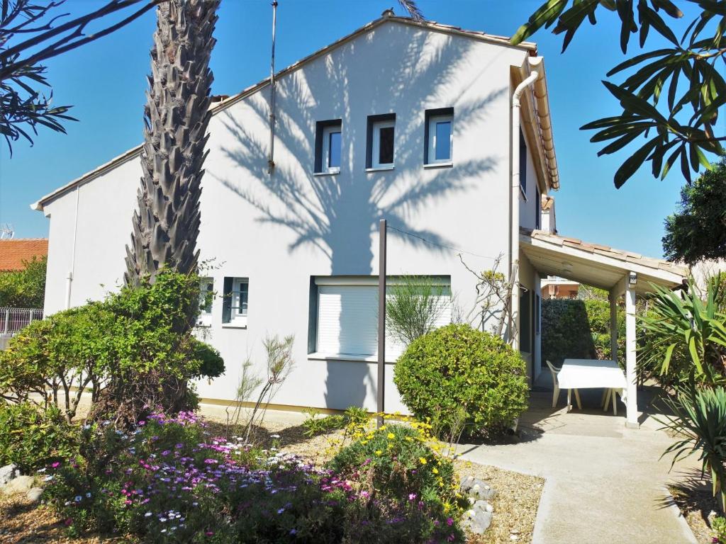 una casa blanca con una palmera y flores en Holiday Home Les Vives by Interhome, en Narbonne-Plage