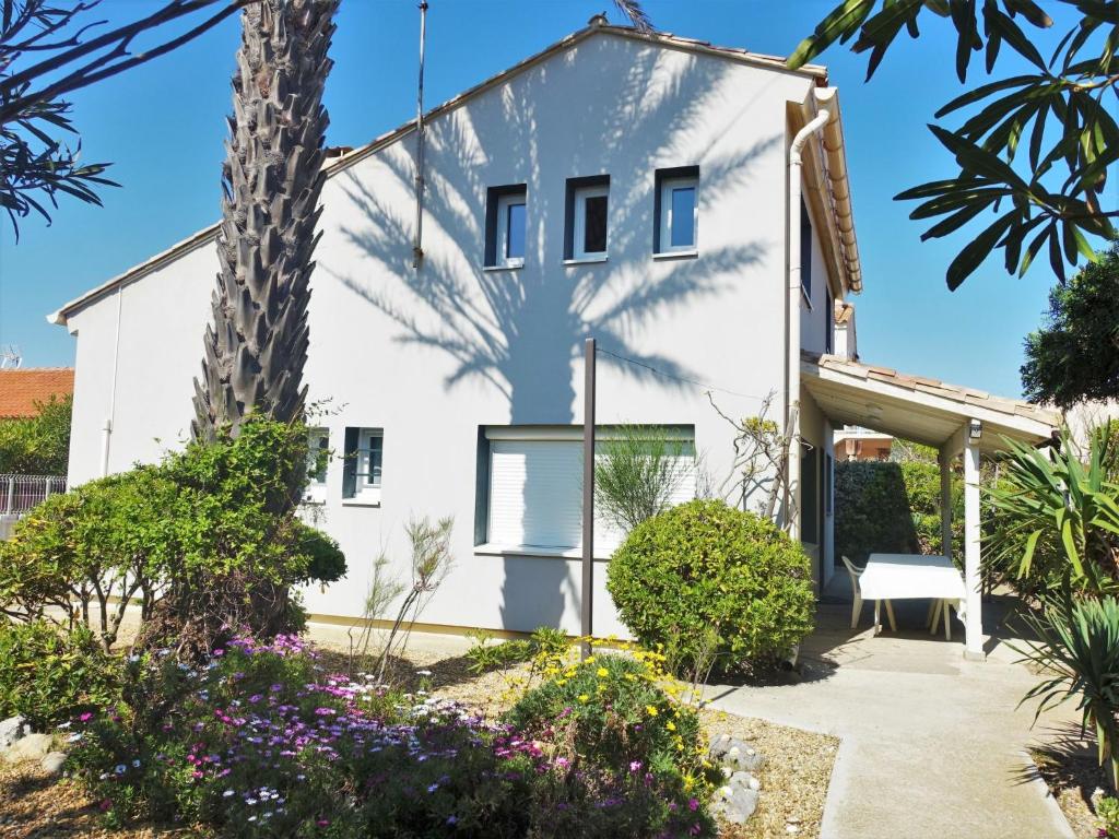 a white house with a palm tree and flowers at Holiday Home Les Vives by Interhome in Narbonne-Plage