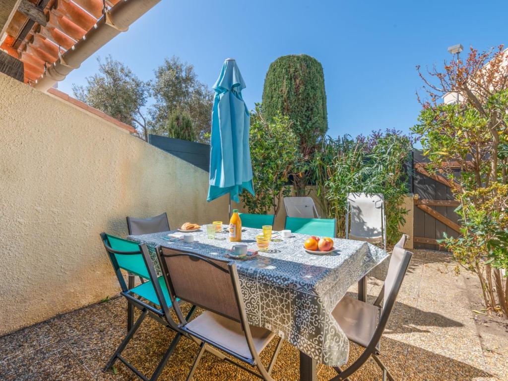 un tavolo con sedie e un ombrellone blu di Holiday Home Les Maisons de la Plage-7 by Interhome a Le Grau-du-Roi