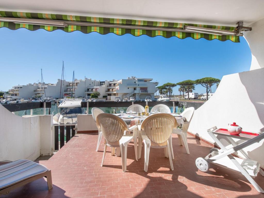 un patio avec une table et des chaises sur un balcon dans l'établissement Apartment Les Marinas de la Plage I-1 by Interhome, au Grau-du-Roi