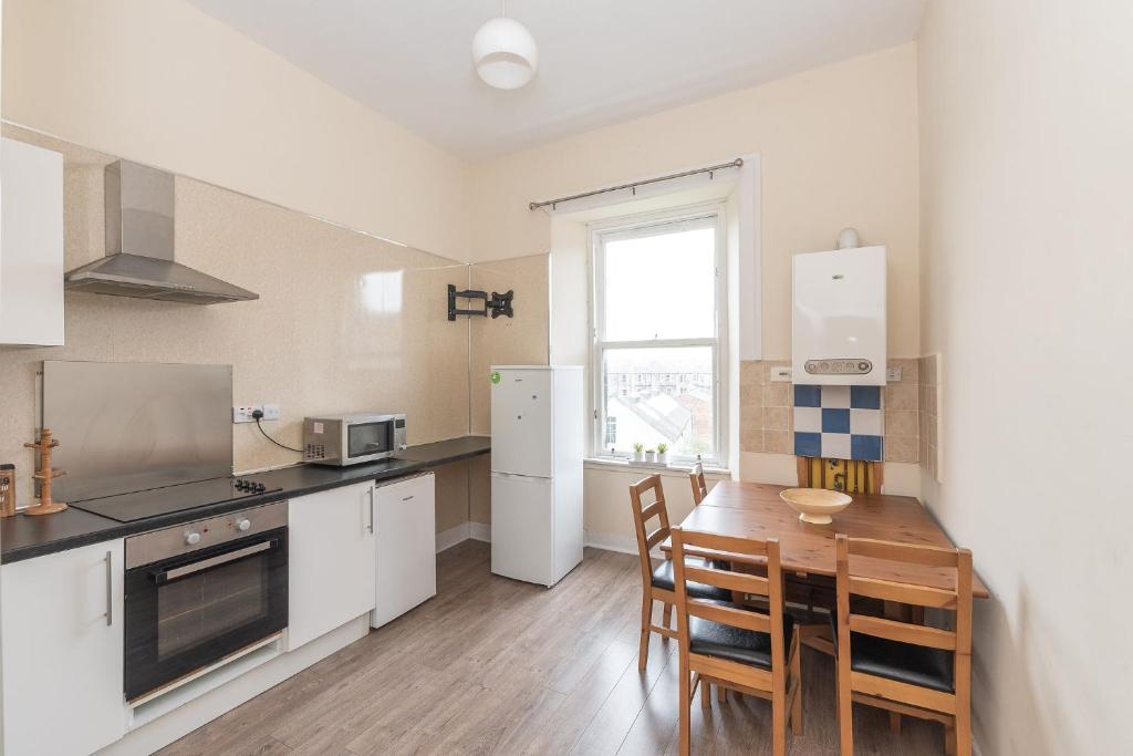 a kitchen with a table and a refrigerator and a window at Contemporary 3 Bed City Centre Appartment - Ensuite in Edinburgh