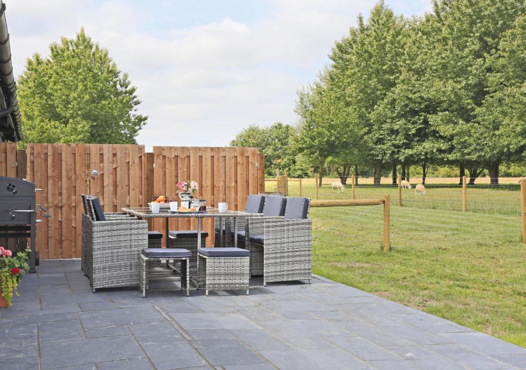 a patio with a table and chairs and a fence at Bluebell Cottage in Beccles