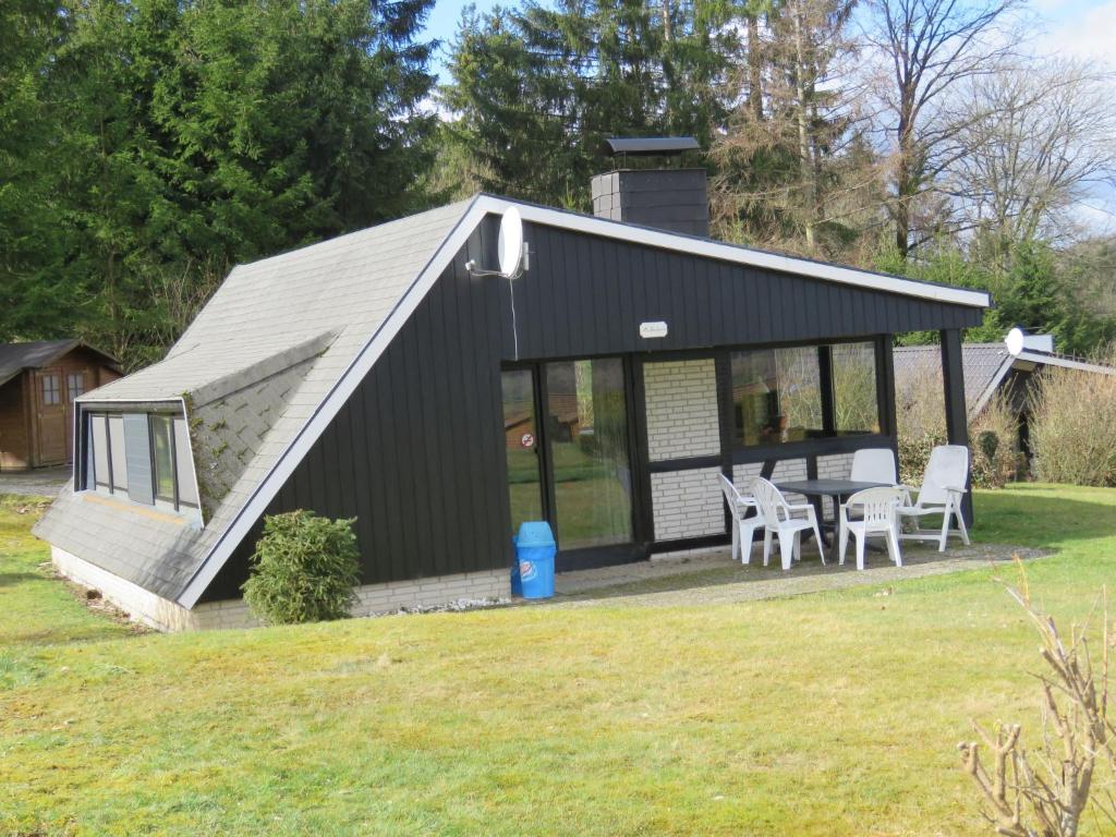 a black shed with a table and chairs in a yard at Holiday Home Waldferienpark Gerolstein-11 by Interhome in Gerolstein