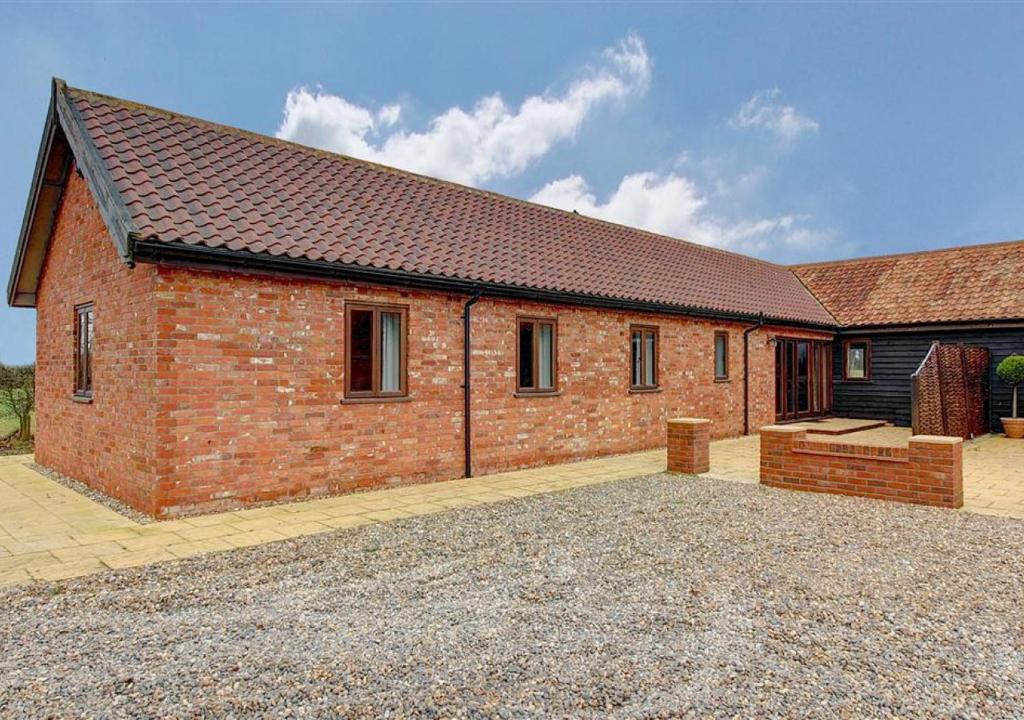 a red brick house with a large driveway at Canola Lodge in Darsham