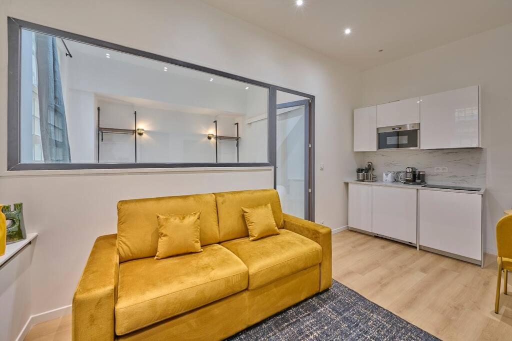 salon z żółtą kanapą i kuchnią w obiekcie Marais - Modern apartment w Paryżu