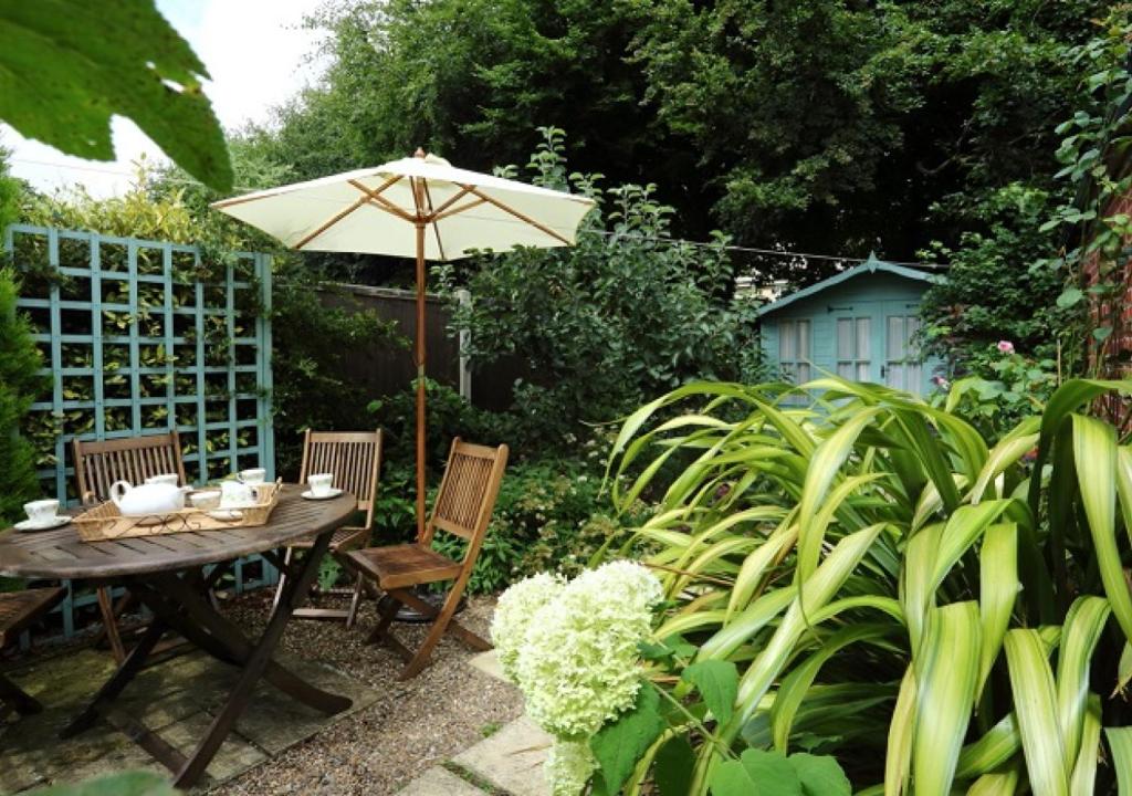 a table and chairs with an umbrella in a garden at Clyde Cottage in Saxmundham