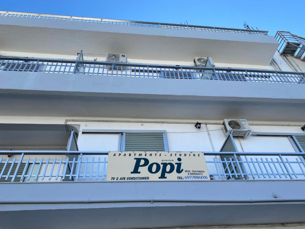 a white building with a sign on a balcony at Popi Studios in Kos