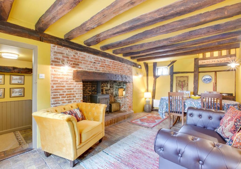a living room with a couch and a fireplace at Cobblers Cottage in Bramfield
