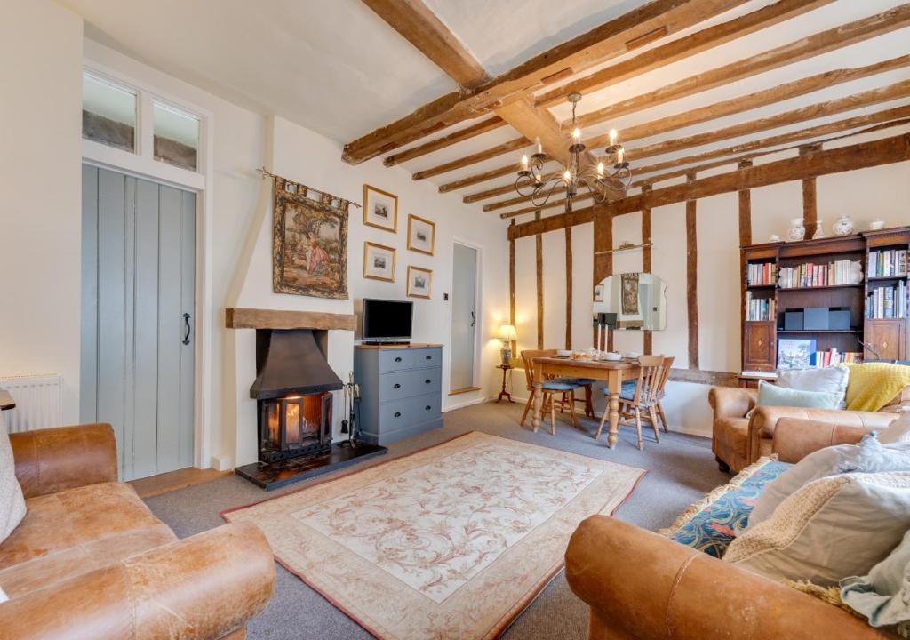 a living room with a fireplace and a couch and a table at Coppers in Lavenham