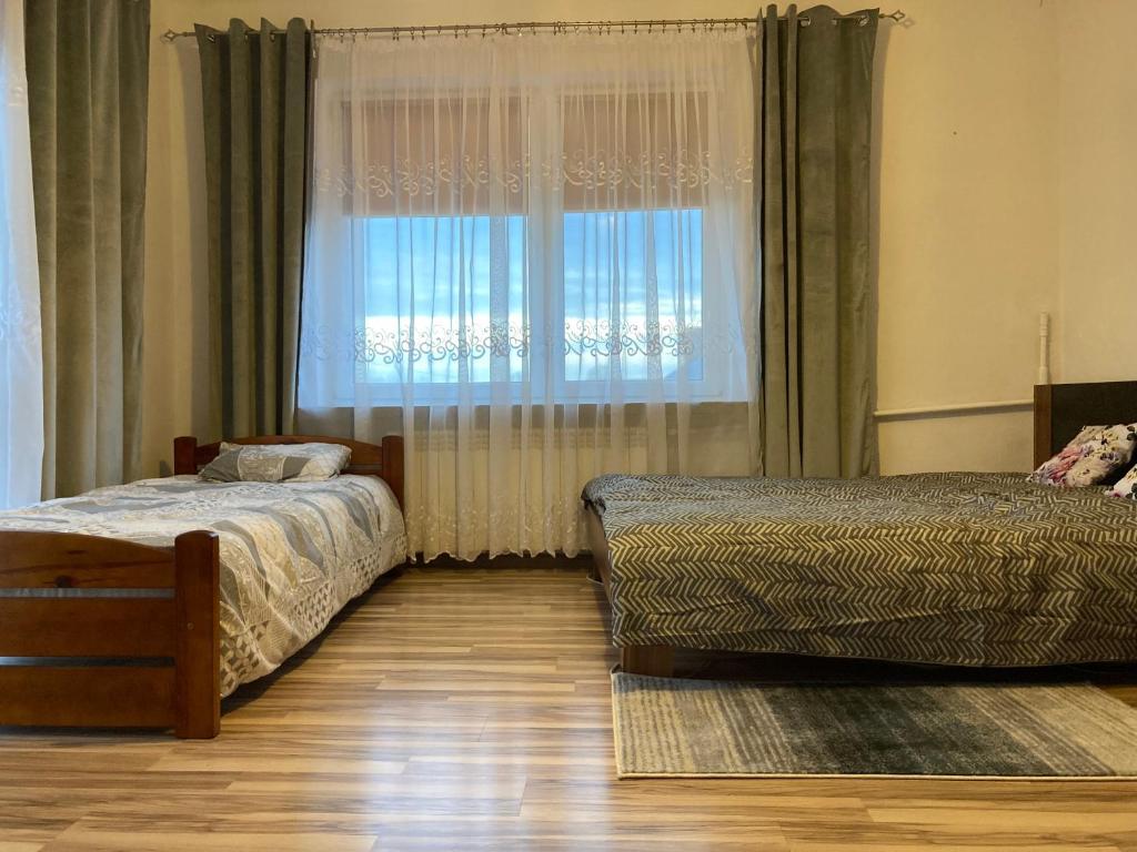 um quarto com 2 camas e uma janela com cortinas em Apartament Villa Olivia em Szczebrzeszyn