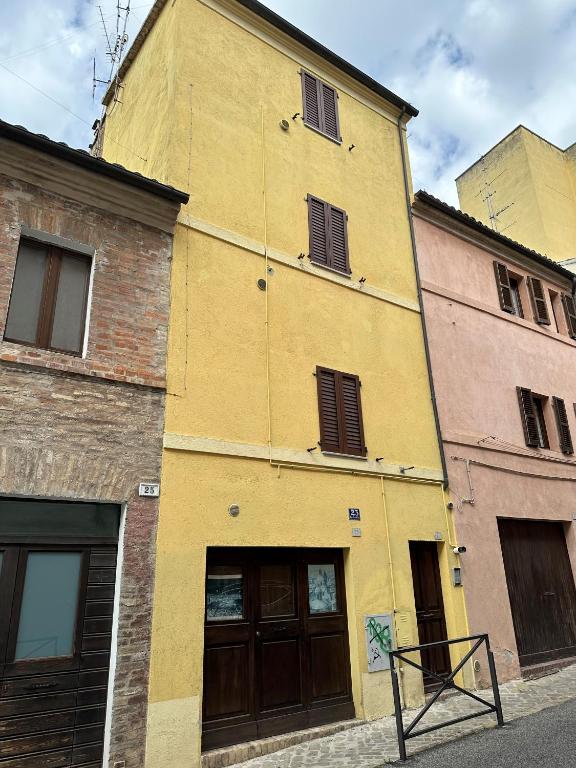 a yellow building with brown doors on a street at L'inchiostro di Dante in Macerata