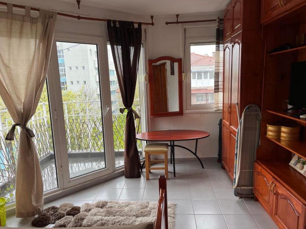um quarto com uma mesa e uma varanda com janelas em Апартамент за гости Сънрайз с гледка към река Дунав em Ruse