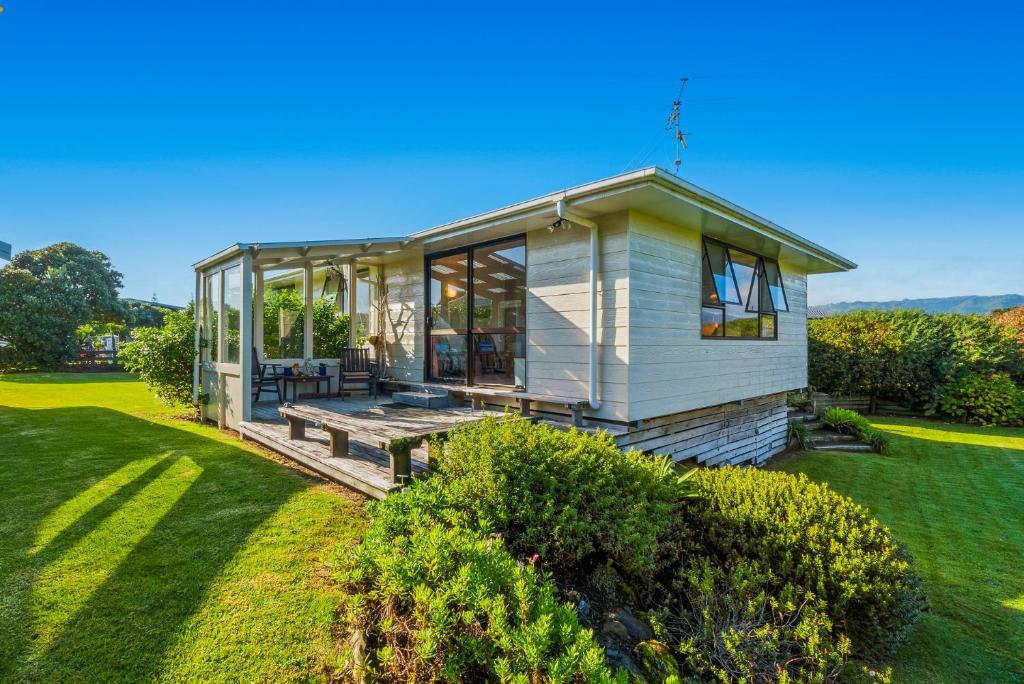 a tiny house on a lawn with a garden at Waikanae Waves - Waikanae Beach Holiday Home in Waikanae