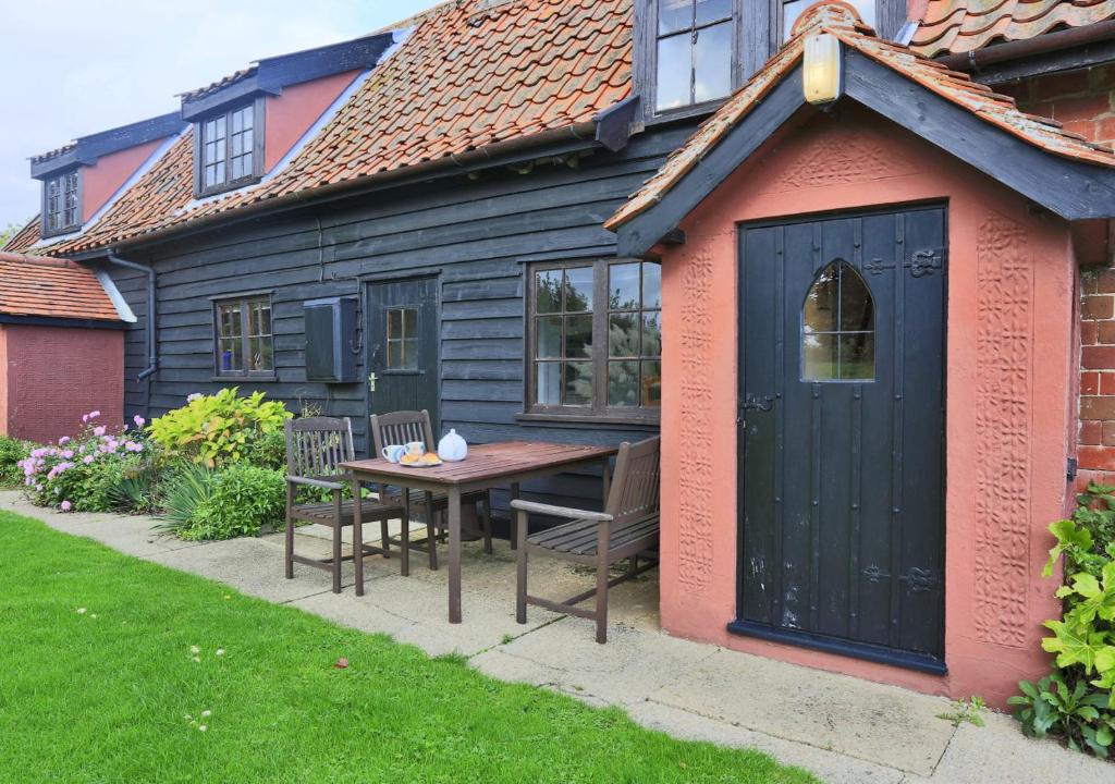 um pequeno barracão com uma mesa e cadeiras em frente a uma casa em Eelsfoot Cottage em Hemley