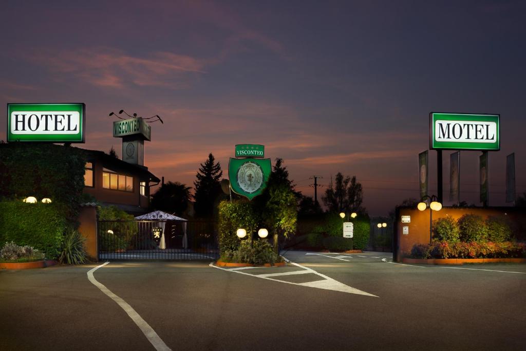 un estacionamiento con un hotel y carteles de motel en Hotel Motel Visconteo en Binasco