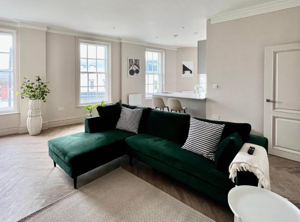 a living room with a green couch and a kitchen at The Apartments Lytham Square in Lytham St Annes