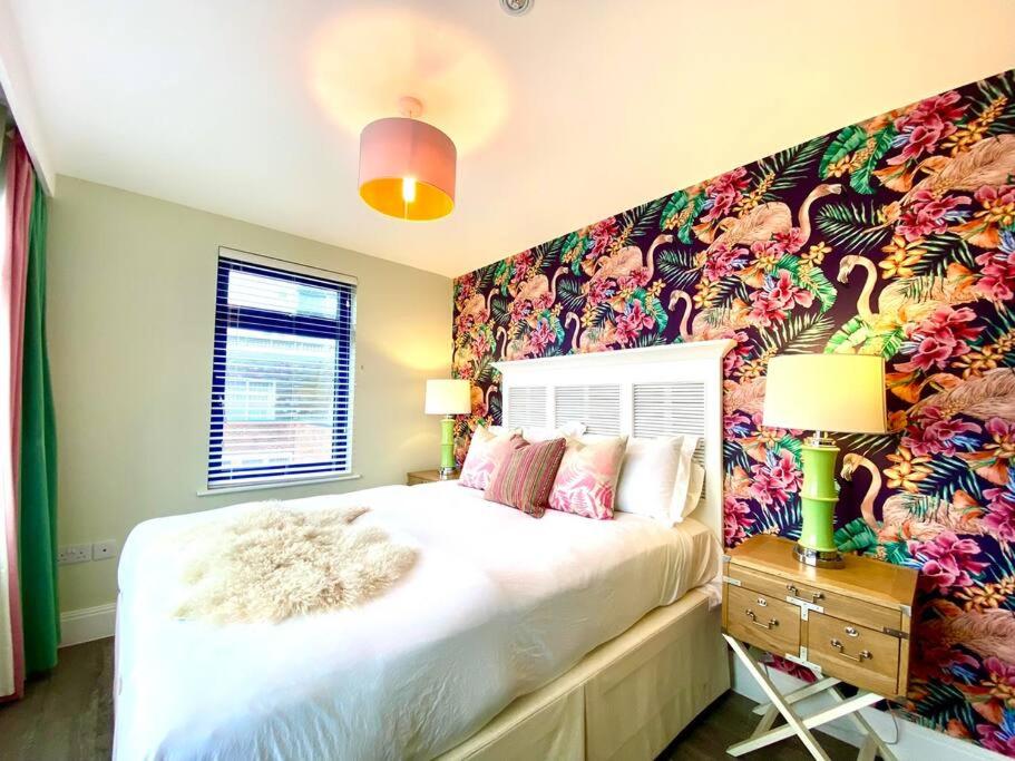 um quarto com uma cama grande e papel de parede floral em Stunning 3 bedroom Penthouse Apartment - Free Parking & WiFi - 1 Minute walk to Poole Quay - Great Location - Free Parking - Fast WiFi - Smart TV - Newly decorated - sleeps up to 6! Close to Poole & Bournemouth & Sandbanks em Poole