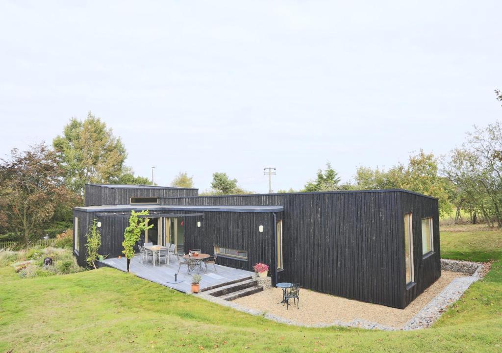a black clad house with a patio in a field at Glenview in Bramfield