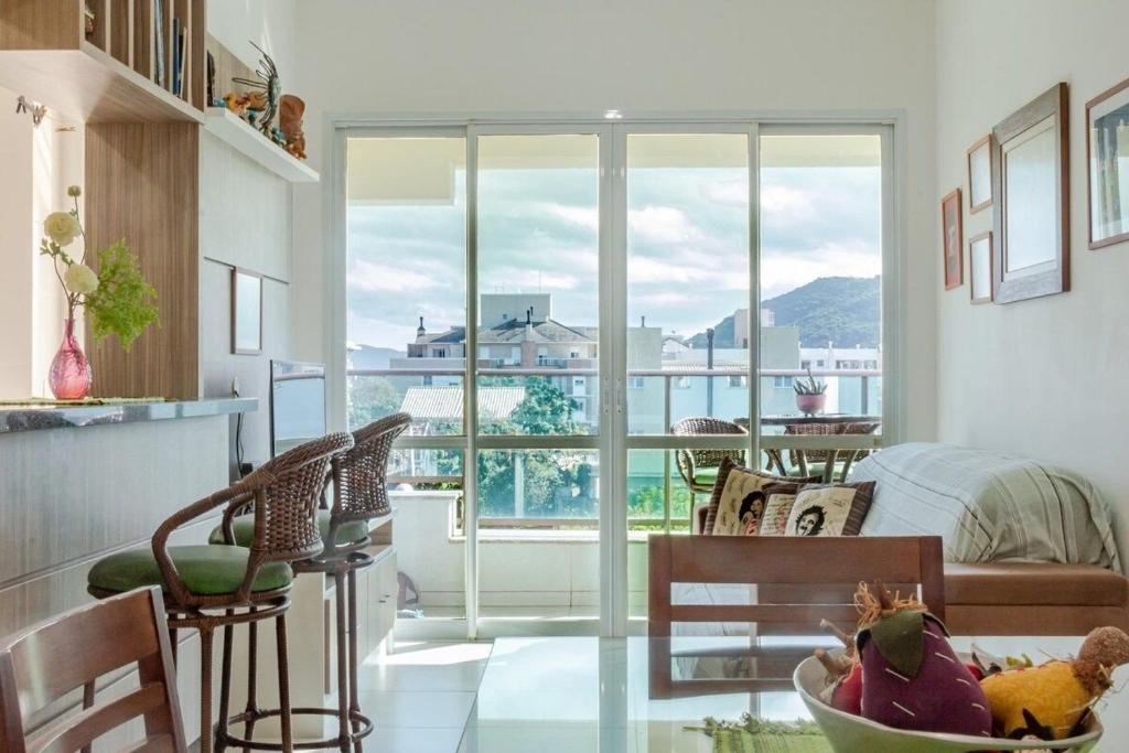 una sala de estar con una gran puerta de cristal con vistas a un dormitorio en Mar do Campeche a 300 m( a pé) . 03 qtos . Varanda, en Florianópolis