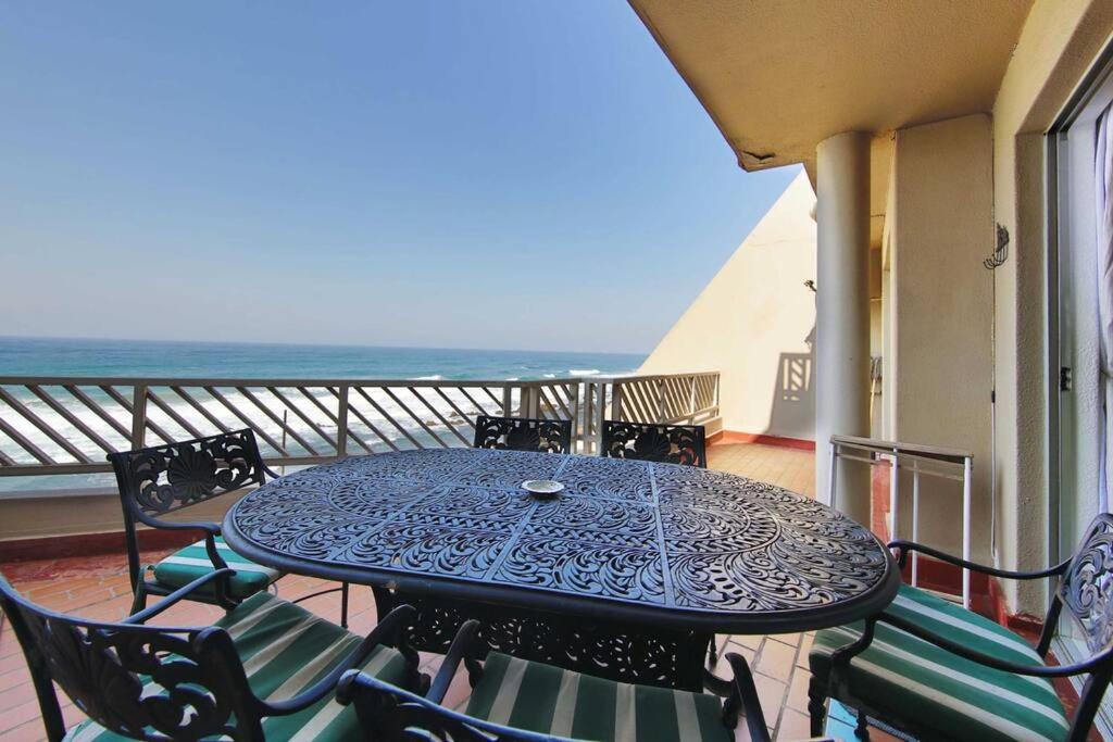einen Tisch und Stühle auf einem Balkon mit Meerblick in der Unterkunft 24 Isikulu Umdloti Beachfront in Umdloti