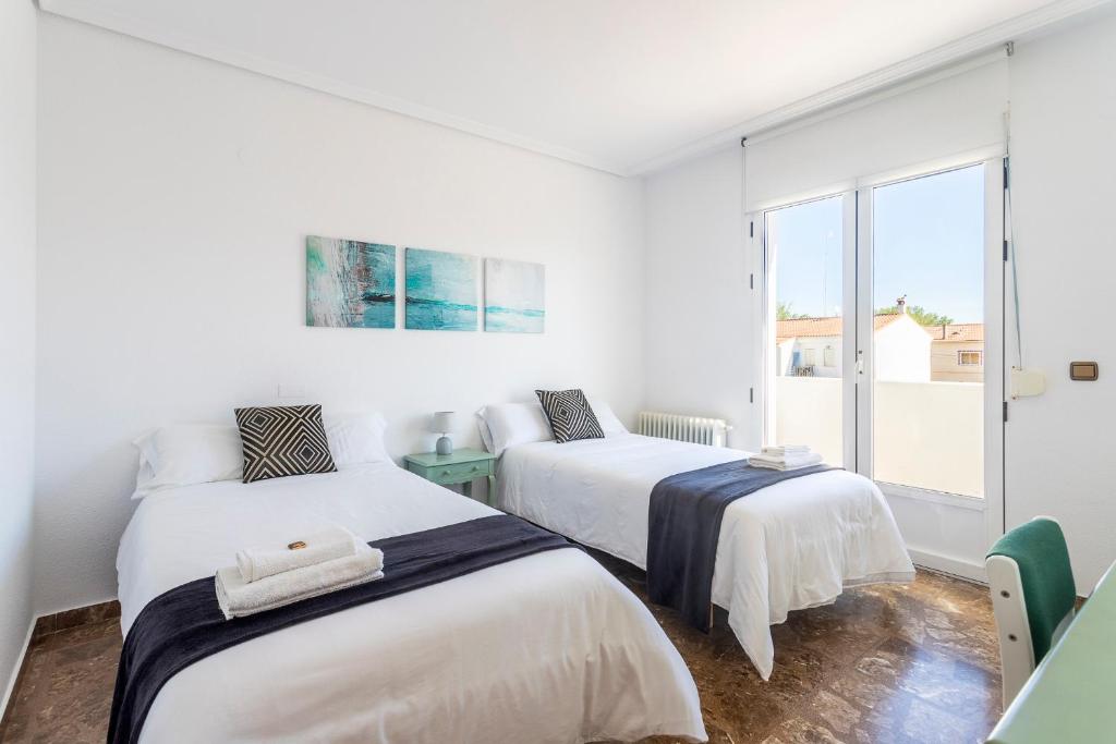 two beds in a white room with a window at Casa Las Rosas in Iniesta