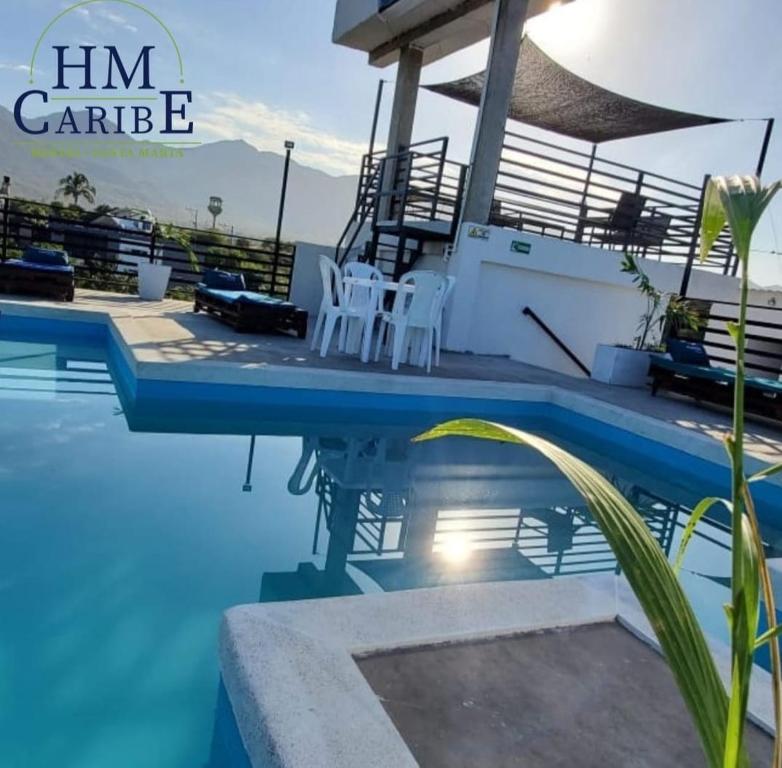a pool with two white chairs next to a house at SUITE GRANDE in Santa Marta