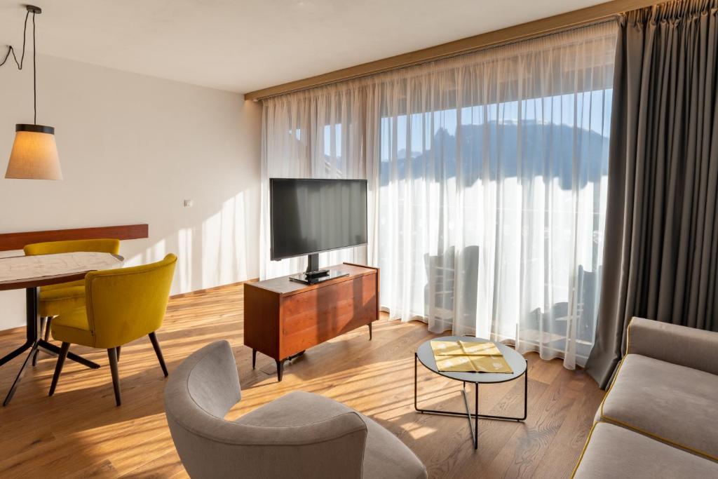 a living room with a television and a table and chairs at Apartments by Bemelmans-Post in Collalbo