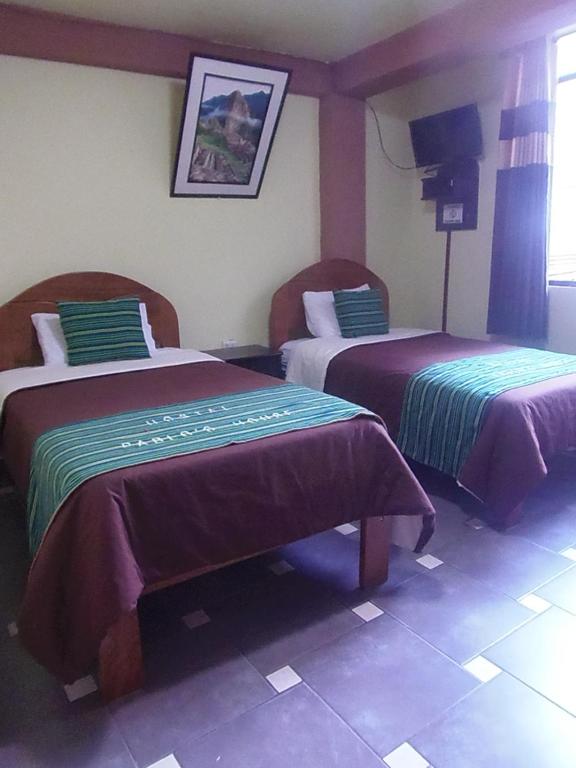 Habitación de hotel con 2 camas con mantas moradas y verdes en Hostal Pablo's House, en Machu Picchu