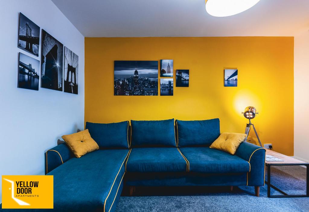 a living room with a blue couch and a yellow wall at Kingscross Neuk - City Base in Dundee