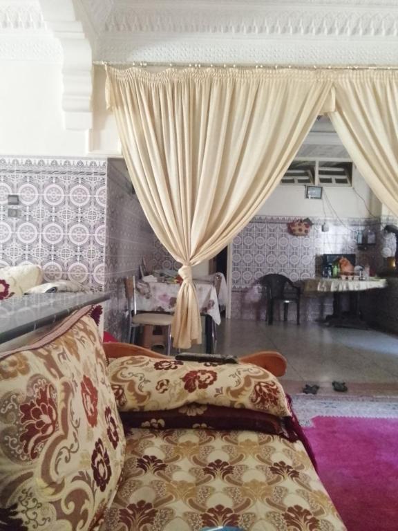 uma sala de estar com um sofá e cortinas em تاغزيفت em Tafraout