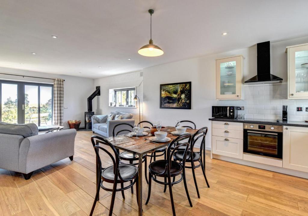 a kitchen and living room with a table and chairs at Little Owl Oxley Dairy in Hollesley