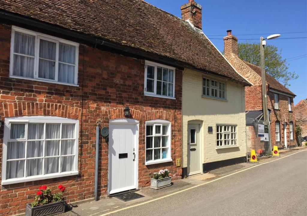 a brick house with white doors and windows on a street at Mariners Cottage in Orford