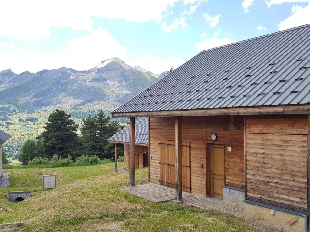 drewniany domek z górami w tle w obiekcie Chalet 6-8 couchages à la Joue du Loup w mieście Dévoluy