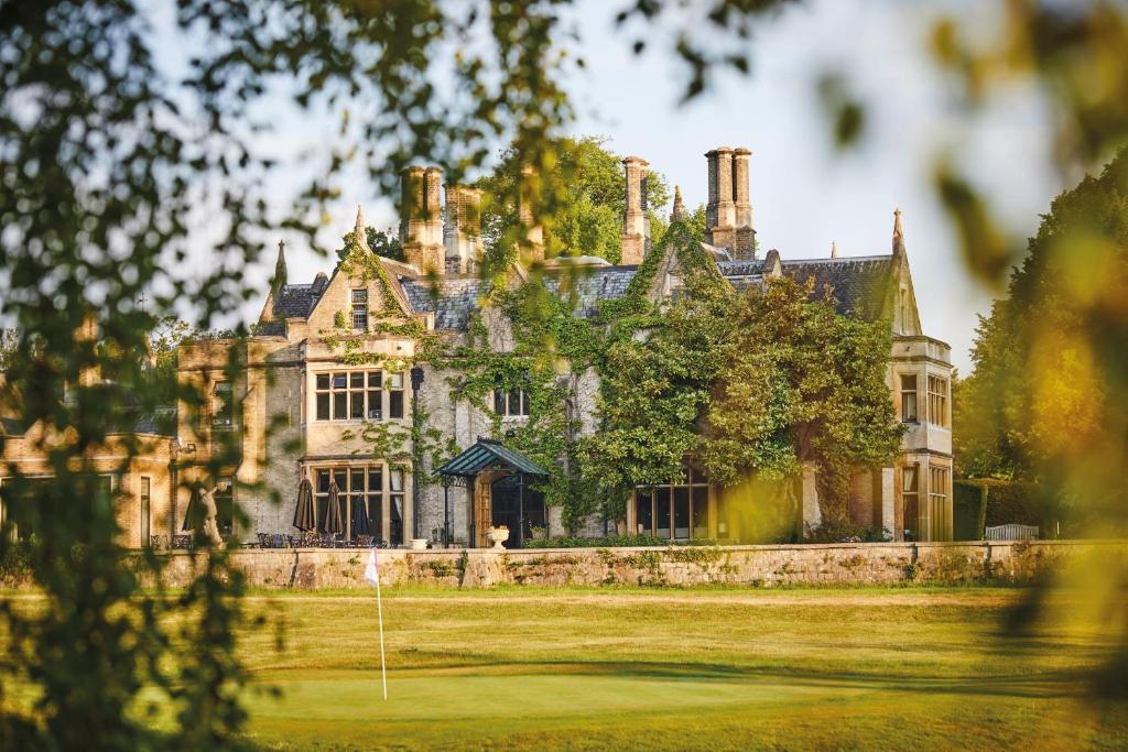 an old mansion with a golf course in front of it at Foxhills Club & Resort in Ottershaw