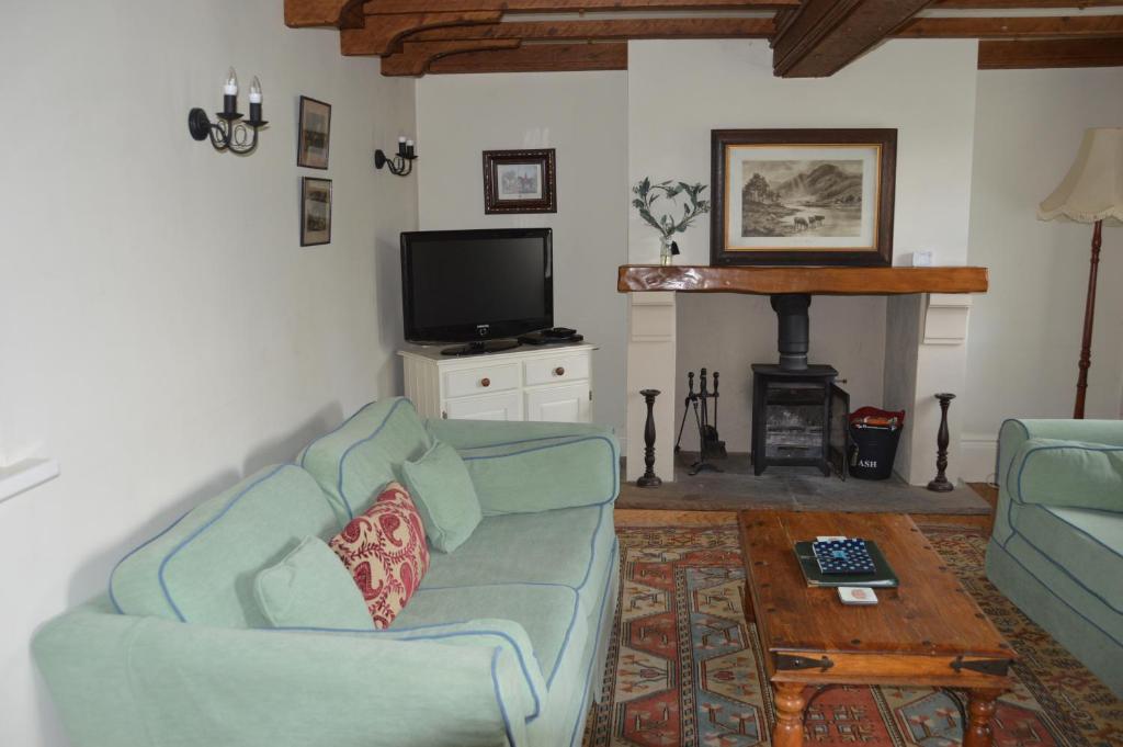 a living room with a couch and a tv at Middlehead Cottages in Pickering